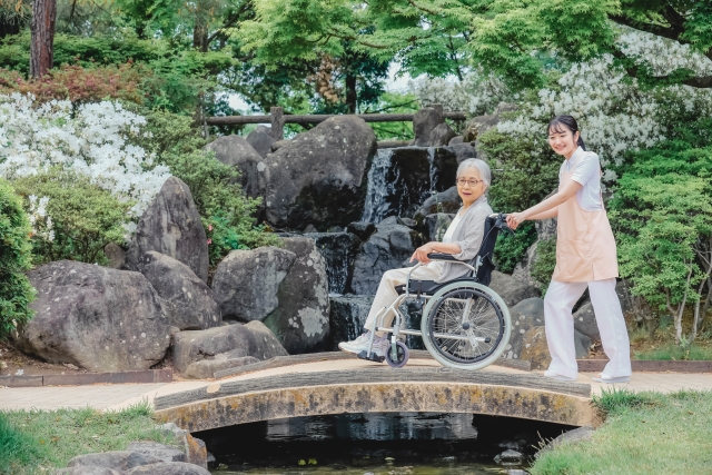 小さな橋を渡る車椅子の女性とスタッフ