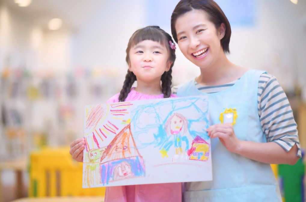 お絵かきを手に笑顔の保育士