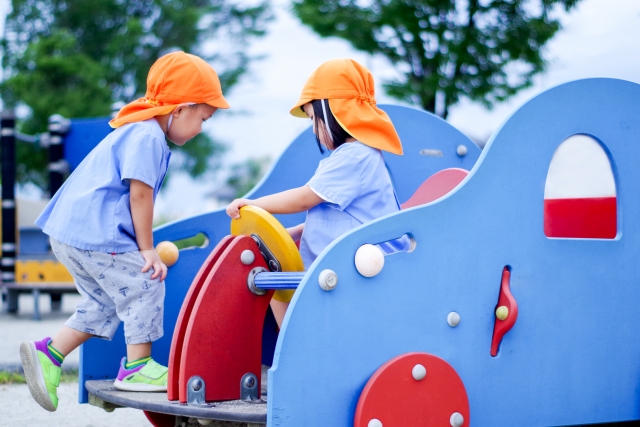 野外の遊具で遊ぶ2人の園児