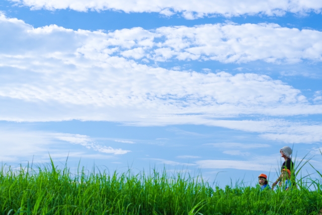 青空の下を歩く大人と子供たち
