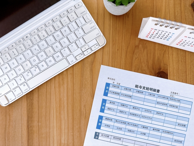 給与支給明細書とキーボードと卓上カレンダー