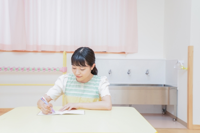 ノートに記入する保育士