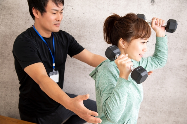 ダンベルを持つ女性とスタッフ